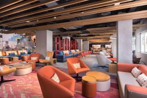 a lobby with orange and blue chairs and tables at Aloft Madrid Gran Via in Madrid