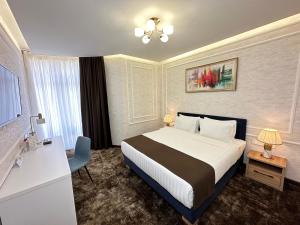 a hotel room with a bed and a desk and a window at Garnet Hotel Tashkent in Tashkent