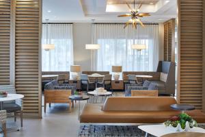 una sala de estar con sofás, mesas y sillas en Residence Inn St. Petersburg Tierra Verde, en Tierra Verde