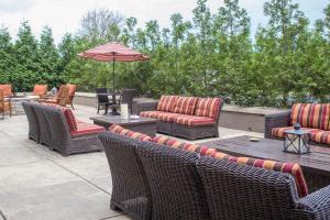 eine Gruppe Stühle und ein Sonnenschirm auf einer Terrasse in der Unterkunft Marriott Louisville East in Louisville