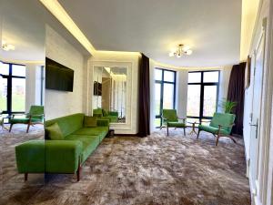 sala de estar con sofá verde y sillas en Garnet Hotel Tashkent, en Tashkent