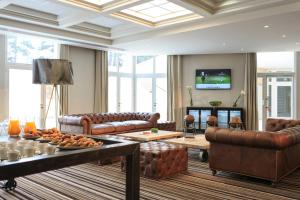 a living room with leather furniture and a tv at Renaissance Paris Hippodrome de St. Cloud Hotel in Rueil-Malmaison