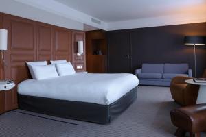 um quarto de hotel com uma cama grande e um sofá em Renaissance Paris Hippodrome de St. Cloud Hotel em Rueil-Malmaison