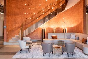 eine Lobby mit einem Sofa, Stühlen und einer Treppe in der Unterkunft AC Hotel by Marriott Wuerzburg in Würzburg