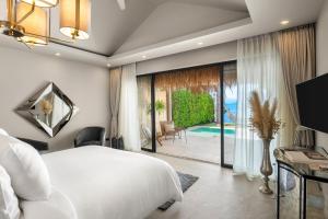 a bedroom with a white bed and a view of a pool at ODYSSEY - Luxury Beachfront Mansion - in Koh Samui