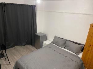 a bedroom with a bed and a black curtain at Hallykins in Erith