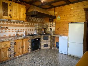 a kitchen with wooden cabinets and a white refrigerator at Гостинний двір in Oryavchyk