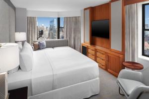 ニューヨークにあるウェスティン ニューヨーク グランドセントラルの白いベッドとテレビが備わるホテルルームです。