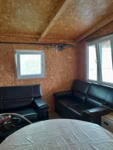 ein Wohnzimmer mit schwarzen Ledersesseln und einem Tisch in der Unterkunft Kapitalac in Banatska Palanka