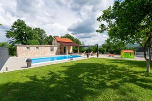 a swimming pool in a yard with a grass field at Kuca za odmor Sliskovic 