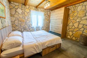 a bedroom with a bed and a stone wall at Kuca za odmor Sliskovic  +30 photos