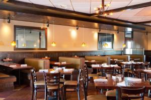 una sala da pranzo con tavoli e sedie in legno di Four Points By Sheraton - Saginaw a Saginaw