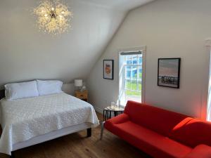 a bedroom with a bed and a red couch at Groundswell Pub & Inn in DʼEscousse