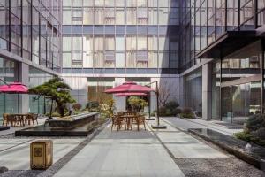 a courtyard with tables and umbrellas in front of a building at Courtyard by Marriott Wenzhou Yueqing in Yueqing