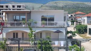 a white house with a balcony and an umbrella at Luxa 5 min old town, 10 min airport in Trogir