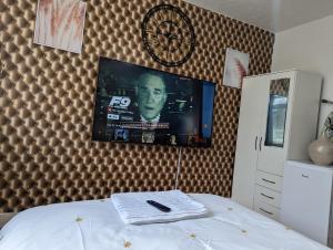 a bedroom with a tv on the wall and a bed at The Saxon Rooms in Barking