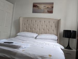 a bedroom with a bed with white sheets and pillows at The Saxon Rooms in Barking