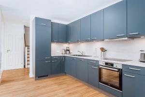 a kitchen with blue cabinets and a wooden floor at Zur Oie 27b in Bresewitz