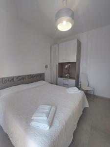 una camera da letto con un grande letto bianco con asciugamani di Hotel San Domingo a Lido di Camaiore