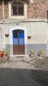 un bâtiment avec une porte et trois plantes en pot dans l'établissement Casa Franchi, à Catane