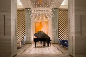 un pianoforte in una stanza con sedie e lampadario a braccio di The St. Regis Astana a Astana