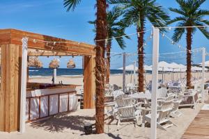 - une table et des chaises sur une plage bordée de palmiers dans l'établissement Wave - Sea Salt Apartment - Pools&SPA, à Międzyzdroje