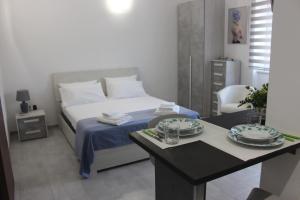 ポザーダにあるElsa e Anna Apartments - Comodi e Rilassanti Appartamentiのベッドと皿が置かれたテーブルのある寝室
