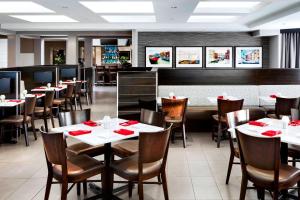 un restaurante con mesas y sillas con servilletas rojas en Four Points by Sheraton Mississauga Meadowvale, en Mississauga