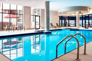 a pool in a hotel with tables and chairs at Four Points by Sheraton Mississauga Meadowvale in Mississauga