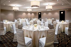 een kamer gevuld met tafels en stoelen met witte tafelkleden bij Four Points by Sheraton Mississauga Meadowvale in Mississauga