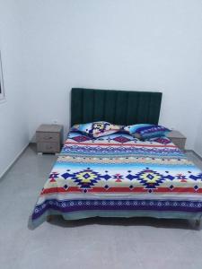 Una cama con una manta colorida y almohadas. en Family corner1, en Ḩammām al Ghazzāz