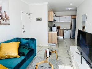 ein Wohnzimmer mit einem blauen Sofa und einer Küche in der Unterkunft The Blyde, an impeccable blissful getaway (Balwin properties) in Pretoria