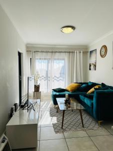 ein Wohnzimmer mit einem blauen Sofa und einem Glastisch in der Unterkunft The Blyde, an impeccable blissful getaway (Balwin properties) in Pretoria
