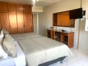 a bedroom with a bed and a desk with a computer at Flat Centro de Brasília - Garvey Park Hotel in Brasilia