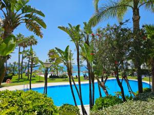 een zwembad met palmbomen in een resort bij Summer House duplex en la playa con piscina in Benalmádena +67 foto's