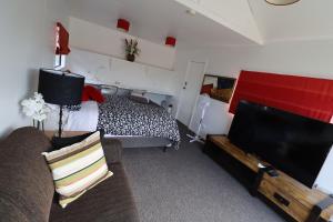 Mapua的住宿－Mapua Fernz，一间卧室配有一张床、一台电视和一张沙发