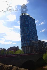 a tall glass building next to a bridge at Heated Floors, High Ceiling, Open Plan, Cosy, Modern, Stylish Sheffield City Centre in Sheffield
