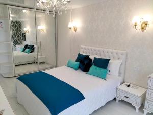 a bedroom with a large white bed with blue pillows at White Apartment in Dnipro