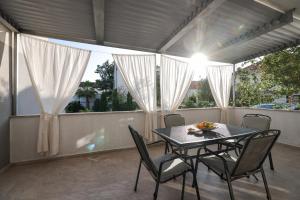 a table and chairs on a balcony with the sun shining at Apartments Mato in Zadar