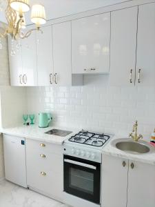 cocina blanca con fogones y fregadero en White Apartment, en Dnipro