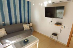 een woonkamer met een bank en een flatscreen-tv bij Apartamento Sol e Mar in Vila Nova de Cacela