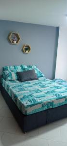 Bett in einem Zimmer mit blauer Wand in der Unterkunft Apartamento con vista al embalse in Guatapé