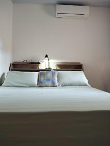 um quarto com uma cama branca e uma luz por cima. em Suíte Santin: o seu conforto está aqui! em Foz do Iguaçu