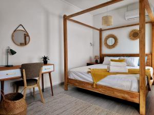Schlafzimmer mit einem hölzernen Himmelbett und einem Schreibtisch in der Unterkunft Villa le Dodo - GBH in Grand Baie