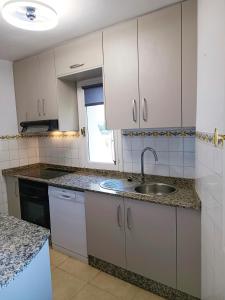 a kitchen with white cabinets and a sink at Los Molinos La Manga Club in Atamaría