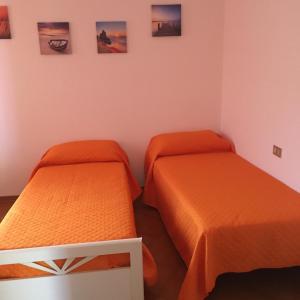2 letti in una camera con lenzuola arancioni di Appartamento Bellavista a Castiglioncello
