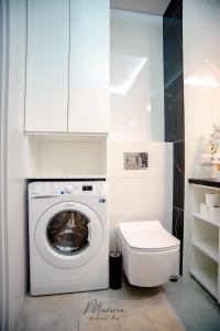a bathroom with a washing machine and a toilet at Marina Apartament 13 Iława - z prywatnym miejscem parkingowym in Iława