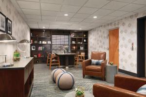a living room with a desk and chairs and a table at Four Points by Sheraton Raleigh Arena in Raleigh