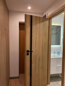 a wooden door in a bathroom with a sink at Apartament 221 przy Niedźwiadku in Polanica-Zdrój