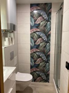 a bathroom with a toilet and a mural of leaves at Apartament 221 przy Niedźwiadku in Polanica-Zdrój
